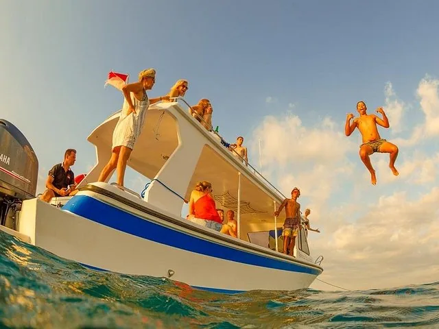 A group of people on a boat, with one person jumping into the water.